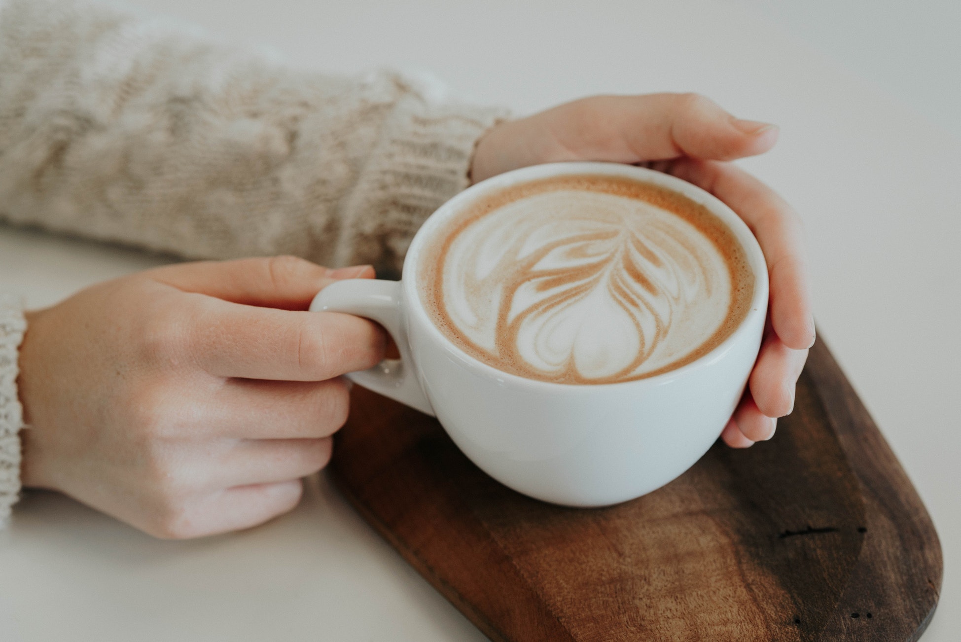 person holding latte in mug